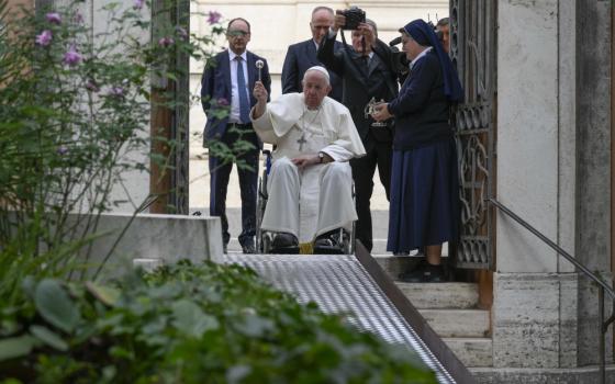 Pope Francis sits in a wheelchair and uses holy water to bless the tombs of those buried in the Vatican's Teutonic Cemetery, a medieval cemetery now reserved mainly for German-speaking priests and members of religious orders, during a visit Nov. 2, 2022, the feast of All Souls. 