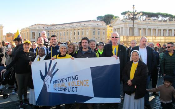 Women religious and men hold a banner that says "Preventing sexual violence in conflict"