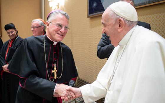 Archbishop Timothy Broglio and Pope Francis shake hands and smile at each other