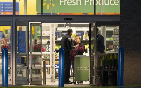 A police officer talks to a female employee at the entrance of a Walmart