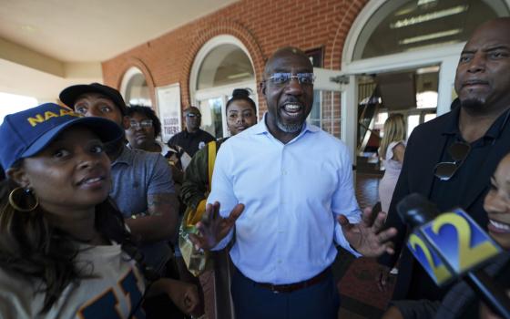 Democratic nominee for U.S Senate Sen. Raphael Warnock speaks to a reporter during a campaign stop on the campus of Morehouse College Tuesday, Nov. 8, 2022, in Atlanta. (AP Photo/John Bazemore)