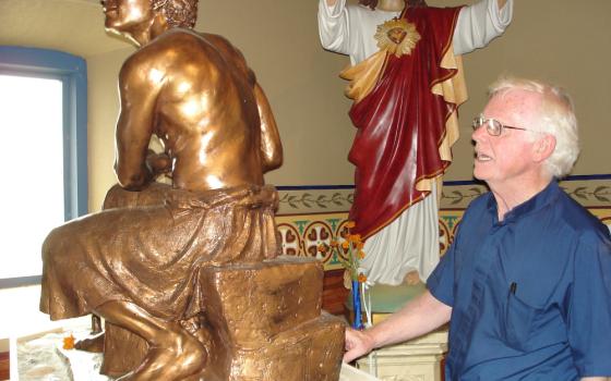 As Fr. Michael Doyle shows the statue he calls "Breakfast on the Beach with Jesus After the Resurrection," the new and old combine in Sacred Heart Parish in a way that expands the idea of Catholic community. (NCR photo/Tom Roberts)