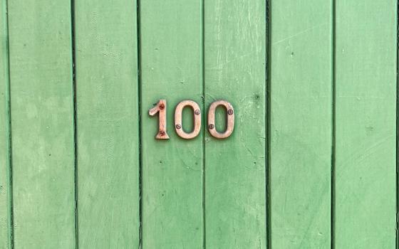 The number 100 on wood slats painted green (Unsplash/Tim Wildsmith)
