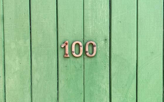 The number 100 on wood slats painted green (Unsplash/Tim Wildsmith)