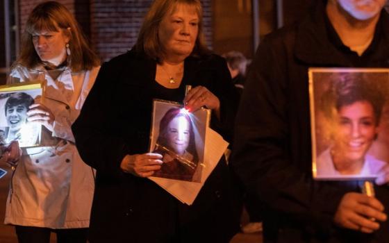 People hold photos of children at vigil for people abused by clergy