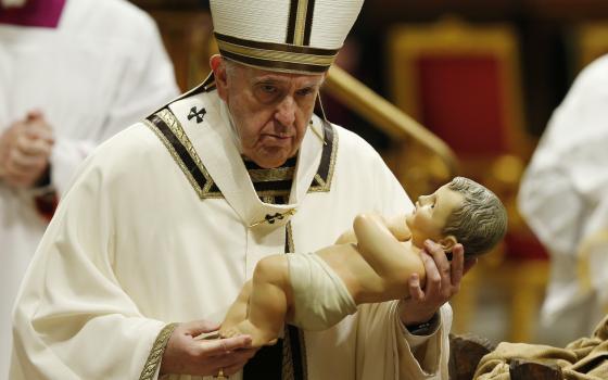 Pope Francis carries a figurine of the baby Jesus at the conclusion of Christmas Eve Mass in St. Peter's Basilica at the Vatican in this Dec. 24, 2021, file photo. (CNS photo/Paul Haring)