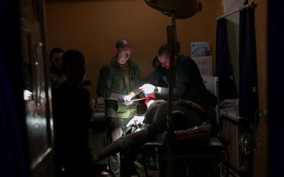 two men treat a patient in a dark room