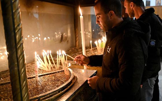 Palestinian Catholic Andrew Bannoura from Bethlehem lights a candle in the grotto of the Church of the Nativity in Bethlehem, West Bank, Dec. 15. (CNS/Debbie Hill)