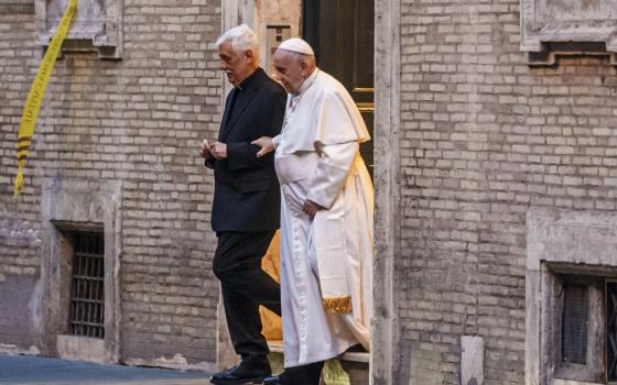 Pope Francis and a priest leave a brick building together