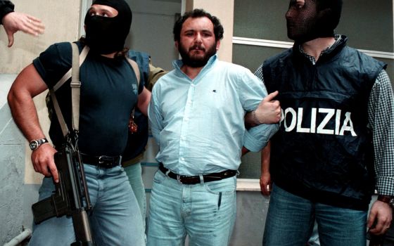 Anti-Mafia police, wearing masks to hide their identity, escort top Mafia fugitive Giovani Brusca as he leaves Palermo's police headquarters to be taken to a maximum security prison, in Palermo, Italy, in this May 21, 1996, file photo.