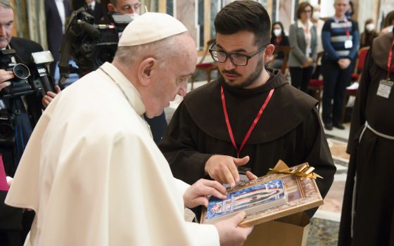 Pope Francis accepts a gift from a Franciscan friar during an audience with a delegation of communicators from the Custody of the Holy Land at the Vatican Jan. 17, 2022. (CNS photo/Vatican Media)