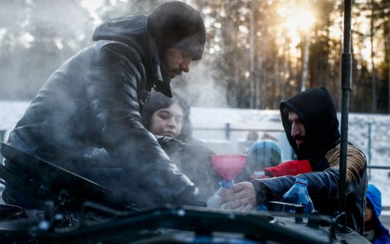 Migrants collect hot water outside the transport and logistics center, Bruzgi, on the Belarusian-Polish border, in the Grodno region of Belarus, in this Dec. 22, 2021. (CNS photo/Maxim Shemetov, Reuters)