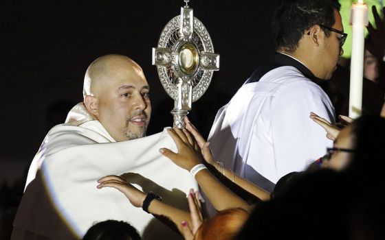 Fr. Joseph Espaillat carries a monstrance through the bleachers of Carnesecca Arena during eucharistic adoration at the Steubenville New York youth conference at St. John's University June 25, 2016, in Jamaica, New York. (CNS/Gregory A. Shemitz)