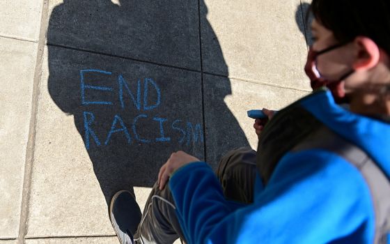 A child in Washington writes in chalk, "End racism," as people rally to protest recent violence against people of Asian descent March 21, 2021. (CNS/Reuters/Erin Scott)