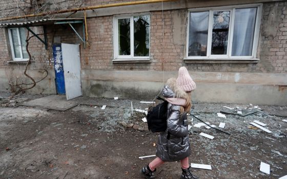 A girl walks past an apartment building damaged by recent shelling in Donetsk, Ukraine, Feb. 24, 2022, after Russian President Vladimir Putin authorized a military operation in Ukraine. (CNS photo/Alexander Ermochenko, Reuters)