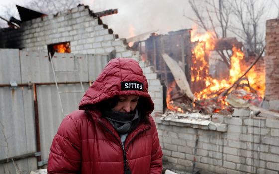 A local resident stands next to her house that caught fire after recent shelling in the separatist-controlled city of Donetsk, Ukraine, Feb. 28. (CNS/Reuters/Alexander Ermochenko)