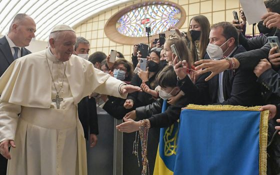 Pope Francis walks near a flag with the national colors of Ukraine during his general audience in the Paul VI hall at the Vatican March 16. (CNS/Vatican Media)