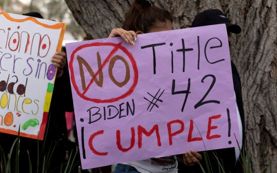 A woman in Nogales, Mexico, holds a sign Nov. 8, 2021, that reads, "No Title 42 Biden ¡Cumple!" at a migrant-led protest against enforcement of the U.S. health code's Title 42 provision, which is being used to keep many migrants out because of concerns ab