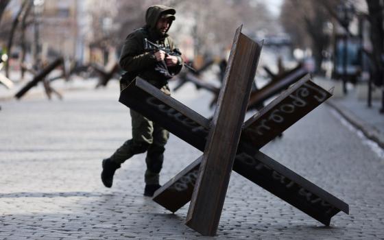A Ukrainian service member walks past an anti-tank barricade reading "Glory to heroes and death to enemies," in downtown Odesa, Ukraine, March 20, 2022. (CNS photo/Nacho Doce, Reuters)