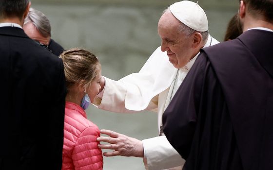 Pope Francis blesses a refugee girl who fled Russia's invasion of Ukraine, during the weekly general audience in the Paul VI hall at the Vatican March 30, 2022. (CNS photo/Guglielmo Mangiapane, Reuters)