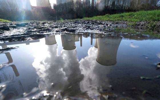 A coal power plant in Neurath, Germany, is seen reflected in a puddle of water Feb. 5, 2020. (CNS/Reuters/Wolfgang Rattay)
