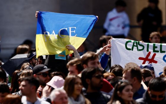 A pilgrim holds a Ukrainian flag as Pope Francis leads the "Regina Coeli" from the window of his studio overlooking St. Peter's Square at the Vatican April 18, 2022. (CNS photo/Yara Nardi, Reuters)