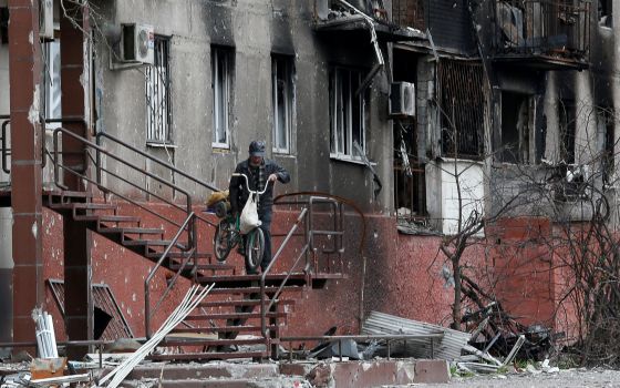 A man walks down the stairs outside a residential building damaged by Russian shelling in Mariupol, Ukraine, April 21, 2022. (CNS photo/Alexander Ermochenko, Reuters)
