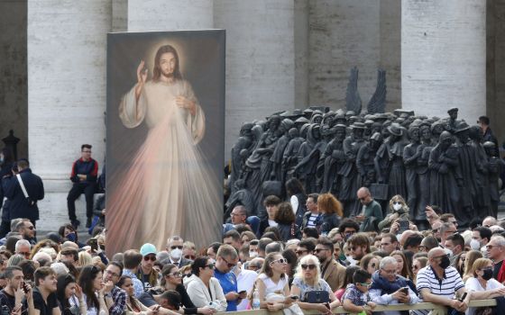 An image of Jesus of Divine Mercy and the "Angels Unawares" sculpture are seen in St. Peter's Square as people wait for Pope Francis to lead the "Regina Coeli" at the Vatican April 24, 2022. (CNS photo/Paul Haring)