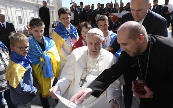 Father Volodymyr Medvid, a chaplain and head of Caritas of the Ukrainian Greek Catholic Church, shows Pope Francis artwork while meeting with a group of Ukrainians after his weekly general audience in St. Peter's Square at the Vatican April 27, 2022. (CNS