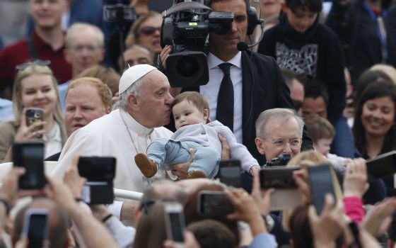 Pope Francis kisses a baby as he greets the crowd during his general audience in St. Peter's Square at the Vatican May 4, 2022. (CNS photo/Paul Haring)