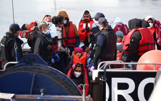 Migrants are escorted by military personnel after being rescued while crossing the English Channel in Dover, England, May 1, 2022. (CNS photo/Henry Nicholls, Reuters)