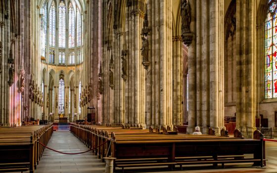 A woman prays in a pew at a nearly empty cathedral in Cologne, Germany, March 16, 2020. (CNS/KNA/Theodor Barth)