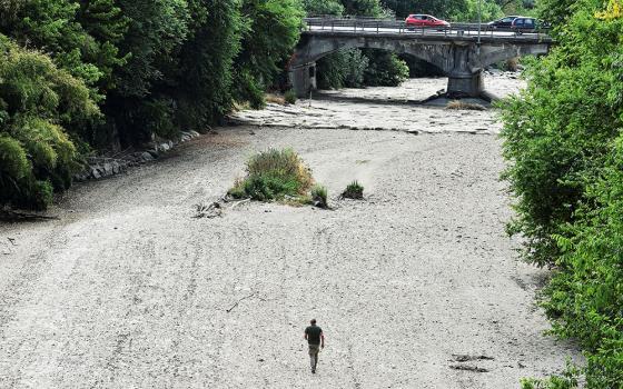 A man walks on the dry riverbed of the Sangone River, a tributary of the Po River, June 19 in Beinasco, Turin, Italy. Italy is experiencing its worst drought in 70 years. (CNS/Reuters/Massimo Pinca)