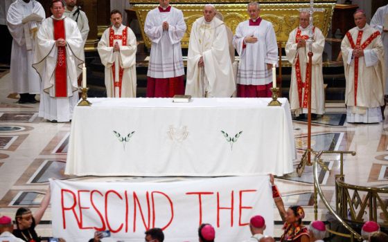 Indigenous people hold a banner calling on Pope Francis to "rescind the doctrine," during a papal Mass at the National Shrine of Sainte-Anne-de-Beaupré in Quebec in this July 28, 2022, file photo. (CNS photo/Guglielmo Mangiapane, Reuters)