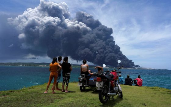 People watch as smoke billows over a large oil storage facility that exploded near Cuba's supertanker port in Matanzas Aug. 8, 2022. The deadly fire is threatening to plunge the island into a deeper energy crisis. (CNS photo/Alexandre Meneghini, Reuters)