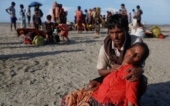 A man who said his village was burned and relatives killed by Myanmar soldiers comforts his wife as Rohingya refugees arrive by a wooden boat from Myanmar in Shah Porir Dwip, Bangladesh, Oct. 1, 2017. 