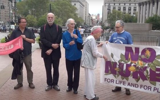 A group of older adults stand outside the courthouse with signs with messages like "No Nukes for life and for planet"