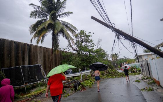 People walk on a street affected by the passing of Hurricane Fiona in Peñuelas, Puerto Rico, Sept. 19, 2022