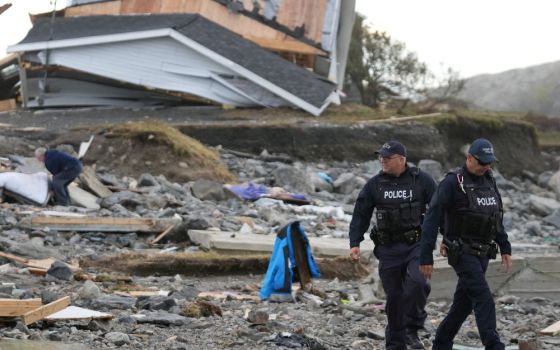 Police officers walk near a destroyed home along the coastline in Port Aux Basques, Newfoundland, Sept. 25, 2022. (CNS photo/John Morris, Reuters)