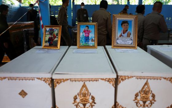 Pictures of victims stand on top of their caskets at Sri Uthai temple in Na Klang, Thailand, Oct. 7, 2022, following a mass shooting in Uthai Sawan
