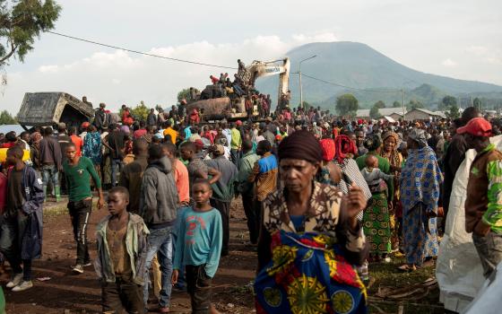 People climb atop a destroyed United Nations peacekeeping truck in Kanyarutshinya, Congo, Nov. 2. The truck was part of a convoy that was attacked when it stopped at an army checkpoint near an internally displaced persons camp. 
