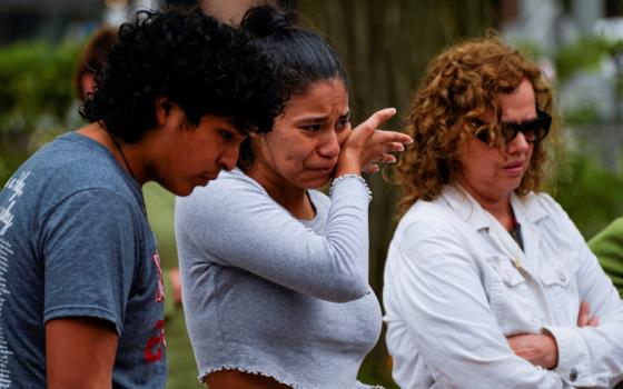 A Brown-skinned young woman, boy, and middle-aged woman look emotional. The young woman wipes a tear.