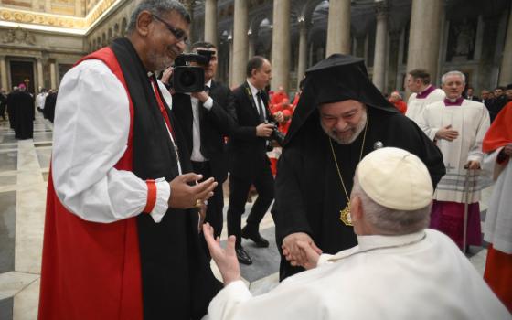 A man wearing a koukoulion, an Orthodox headdress, shakes Pop Francis' hand, as a Brown man with Black and red vestments stands next to him.