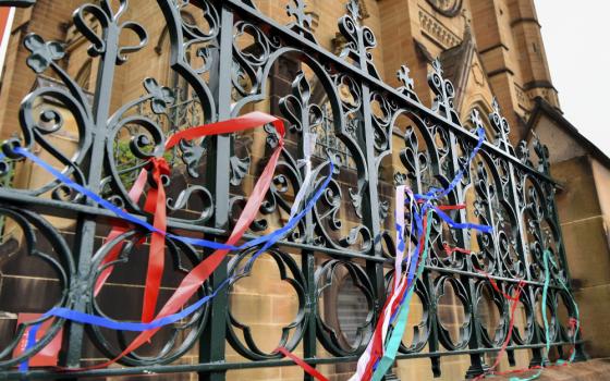 Long colorful ribbons are intertwined with the metal ornamentation of a fence outside a cathedral