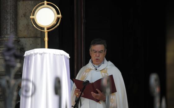 A white archbishop reads from a formal book inside a sanctuary