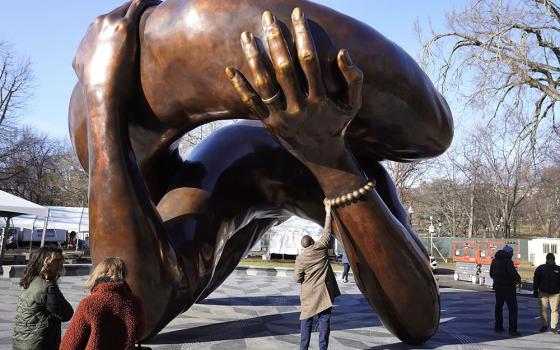 A man reaches to touch a detail of the 20-foot-high bronze sculpture "The Embrace," a memorial to Dr. Martin Luther King Jr. and Coretta Scott King, in the Boston Common Jan. 10 in Boston. The statue was officially unveiled during ceremonies Jan. 13. (AP/Steven Senne)