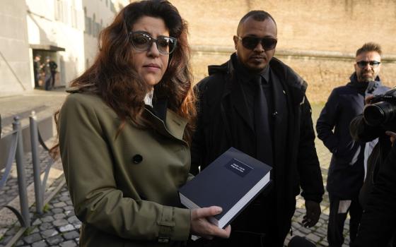 Public relations specialist Francesca Chaouqui, previously financial consultant for the Vatican, shows reporters documents, as she arrives for testimony in a trial in the city-state's criminal tribunal, Friday, Jan. 13, 2023. 