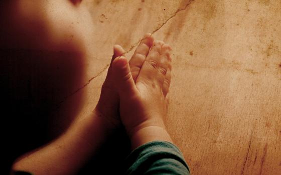 The hands of a child praying (Dreamstime/Arybickii)
