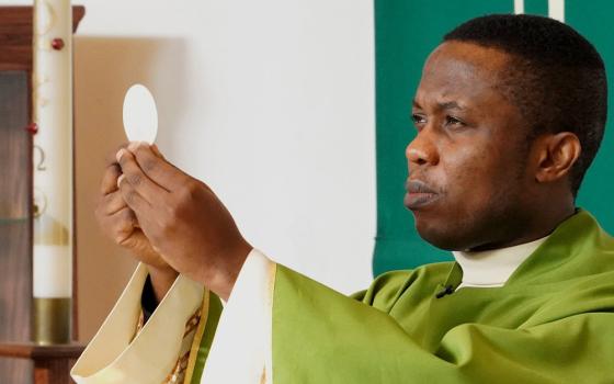 Fr. Patrick Ojiakor, a priest from the Diocese of Onitsha, Nigeria, raises the host during Mass Jan. 19, 2020, at a church in Central Islip, New York. (CNS/Gregory A. Shemitz)