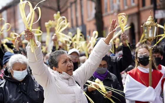 The faithful raise their palm fronds as they participate in a Palm Sunday procession April 10, 2022, in the Prospect Heights section of Brooklyn, New York. (CNS/Gregory A. Shemitz)